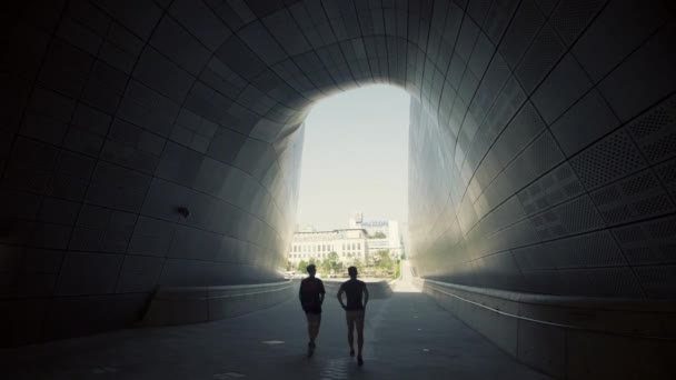 Güney Kore, Seul 'de Dongdaemun Tasarım Plaza' da bir geçitten geçen iki kişi. — Stok video
