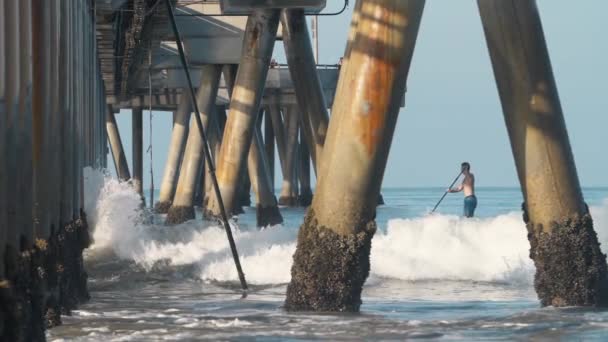 Strzał w zwolnionym tempie mężczyzny na paddleboardzie pod Venice Fishing Pier w La — Wideo stockowe