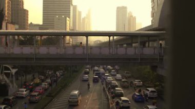 Ağır çekim, Bangkok, Tayland 'da yoğun bir yol üzerindeki yaya köprüsünün görüntüsünü ortaya çıkardı.