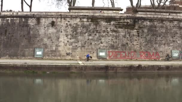Egy személy, aki a Tiber folyó partján kerékpározik Rómában. — Stock videók