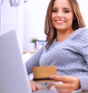 Bilgisayarı ve kredi kartıyla gülümseyen güzel bir kadın.