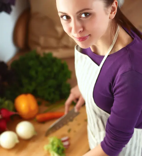 Mujer joven cortando verduras en la cocina — Foto de Stock