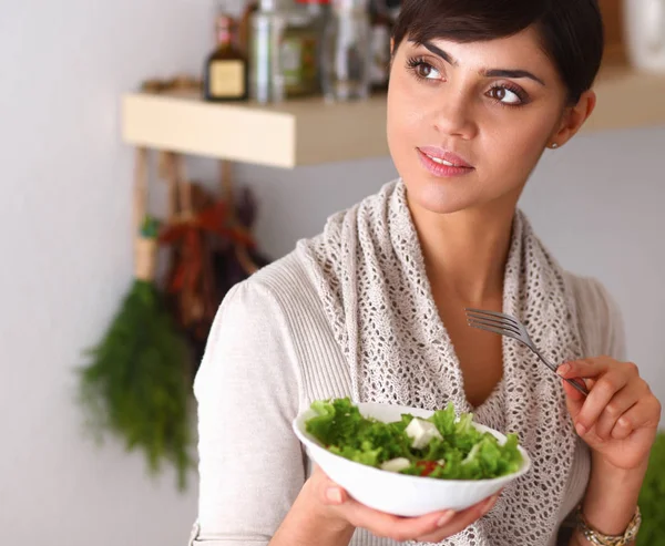 Mujer joven comiendo ensalada fresca en la cocina moderna —  Fotos de Stock