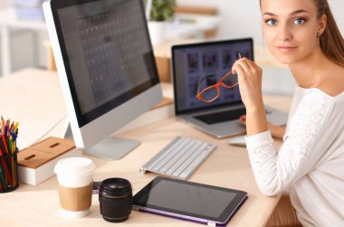 Ofiste çalışan genç bir kadın, masada oturuyor.