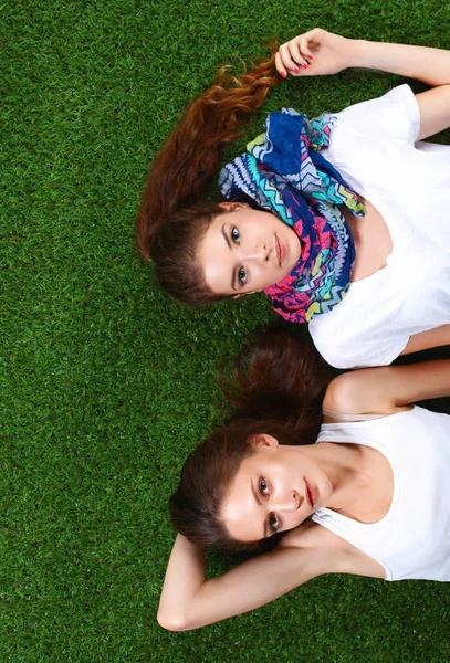 Dos chicas guapas tumbadas en la hierba verde fresca — Foto de Stock