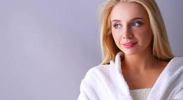 Smiling woman in white bathrobe, isolated on gray background — Stock Photo, Image