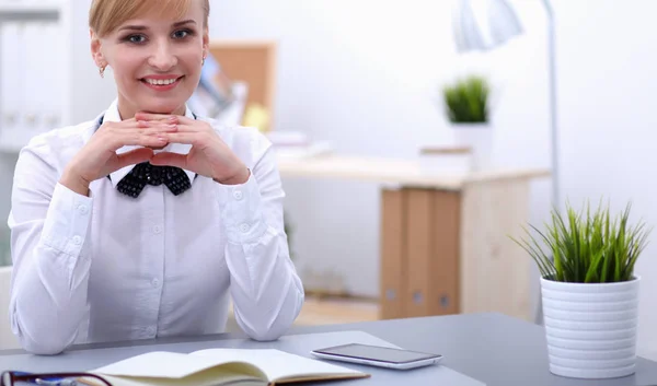 Mulher sorridente sentada na mesa no escritório — Fotografia de Stock