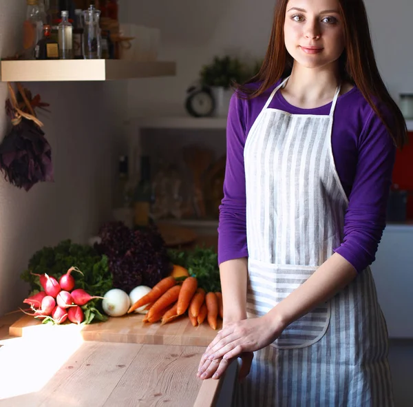 Jonge vrouw in haar keuken in de buurt van Bureau met shopping tassen — Stockfoto