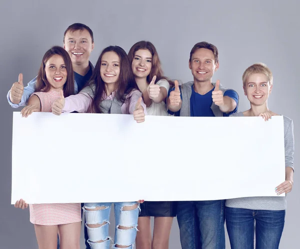 Happy young group of people standing together and holding a blank — Stock Photo, Image