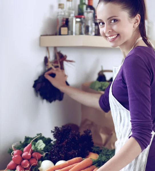 Young woman standing in her kitchen near desk with shopping bags — Stock Photo, Image