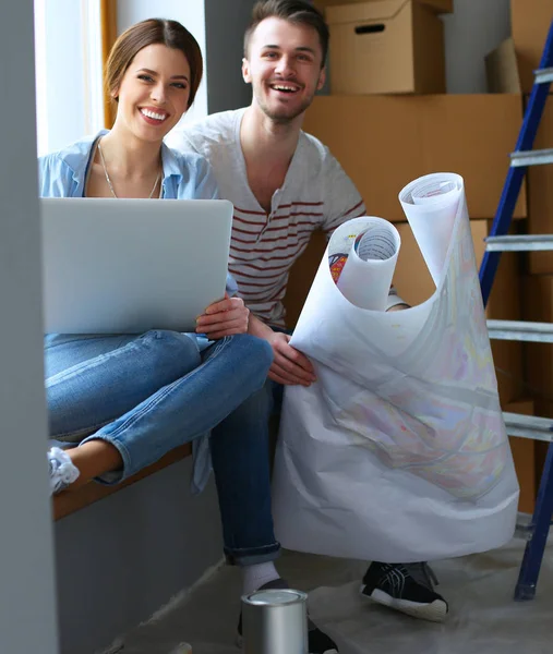 Unga par sitter på golvet och tittar på ritningen av ett nytt hem — Stockfoto