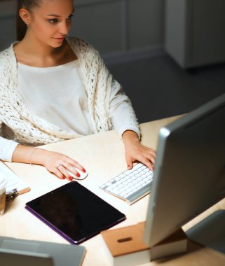 Ofiste çalışan genç bir kadın, masada oturuyor.