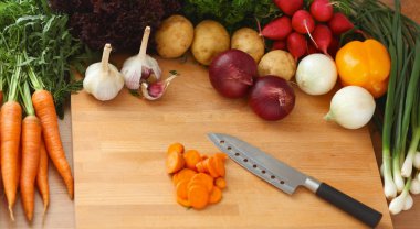 Mutfaktaki masanın üstünde sebzeler var.