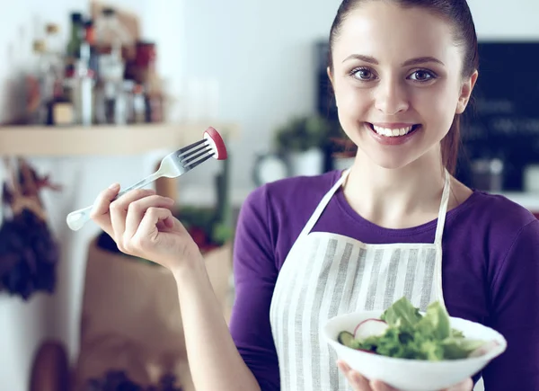 Young woman eating fresh salad in modern kitchen — Stock Photo, Image