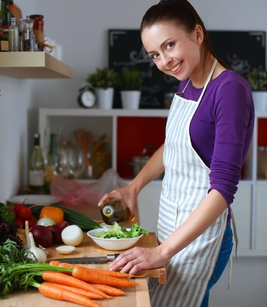 Jonge vrouw die groenten snijdt in de keuken — Stockfoto