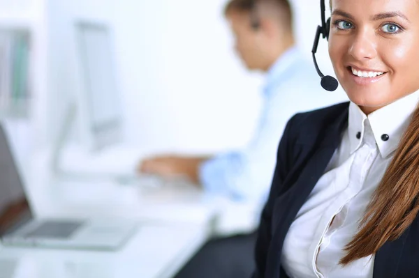 Gelukkig vrouwtje draagt een headset en zit op het bureau — Stockfoto