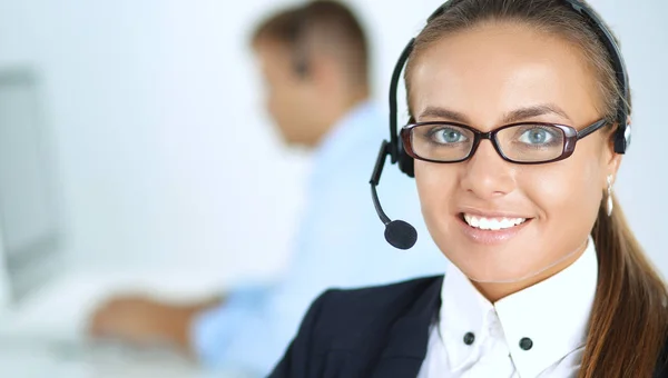 Glückliche Frau trägt Headset und sitzt auf dem Schreibtisch — Stockfoto