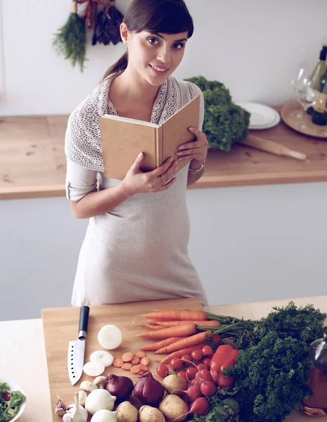주방에서 요리 책을 읽고 있는 젊은 여자가 요리법을 찾고 있다 — 스톡 사진