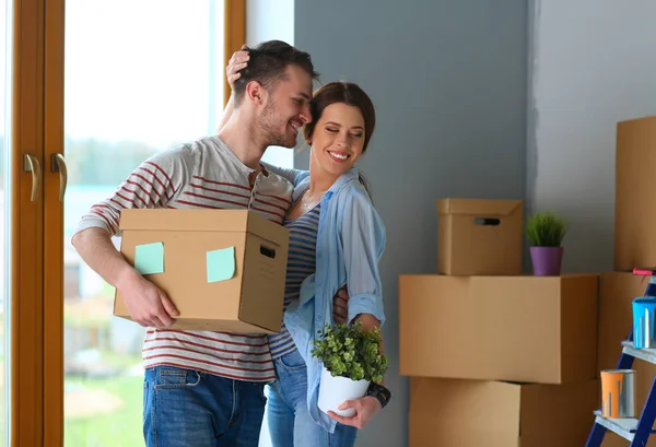 Feliz jovem casal desembalagem ou embalagem caixas e se mudar para uma nova casa — Fotografia de Stock