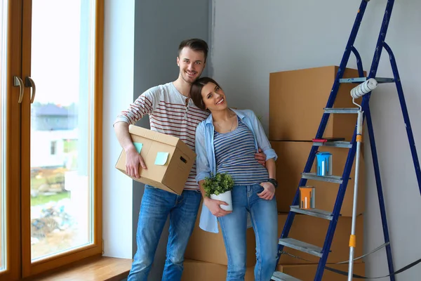 Feliz jovem casal desembalagem ou embalagem caixas e se mudar para uma nova casa — Fotografia de Stock