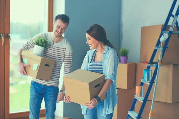 Feliz pareja joven desempacar o empacar cajas y mudarse a un nuevo hogar — Foto de Stock