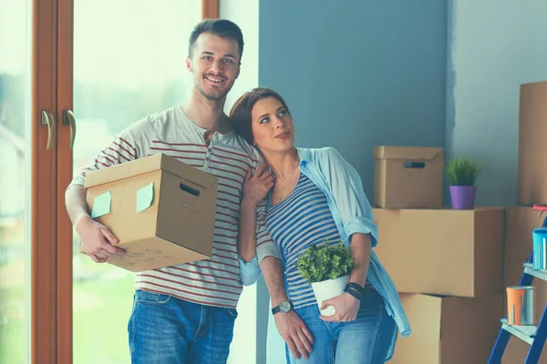 Feliz jovem casal desembalagem ou embalagem caixas e se mudar para uma nova casa — Fotografia de Stock