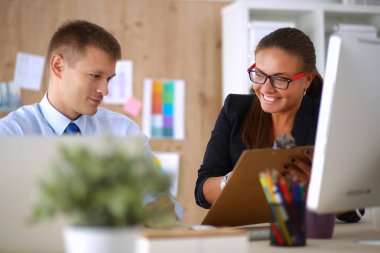 Moda tasarımcıları stüdyoda çalışıyor. Masanın üzerinde oturuyorlar.