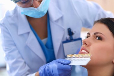 Kadın dişçi hastalarının dişlerinde çalışıyor.