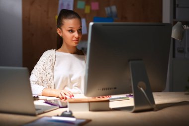 Ofiste çalışan genç bir kadın, masada oturuyor.