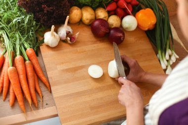 Mutfakta sebze doğrayan genç bir kadın.