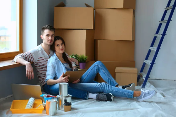 Ungt par sitter på golvet i deras nya lägenhet — Stockfoto