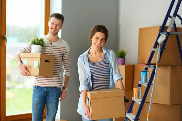 Feliz jovem casal desembalagem ou embalagem caixas e se mudar para uma nova casa — Fotografia de Stock