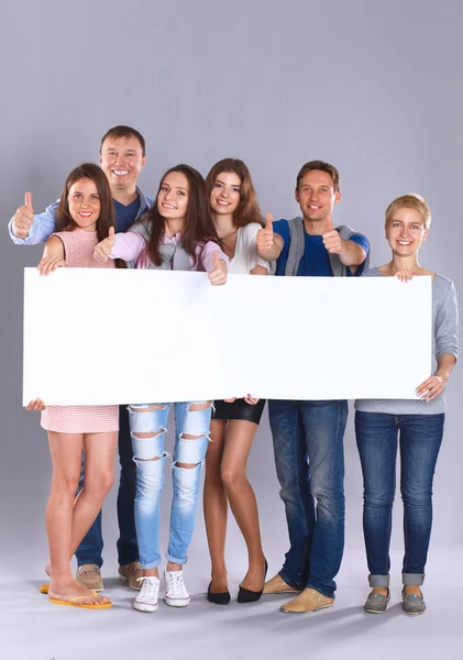 Happy young group of people standing together and holding a blank — Stock Photo, Image