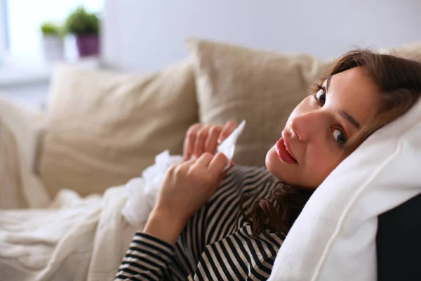 Porträt einer kranken Frau, die sich auf dem Sofa die Nase pustet — Stockfoto