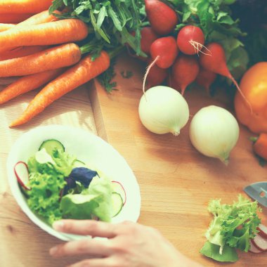 Mutfakta sebze doğrayan genç bir kadın.