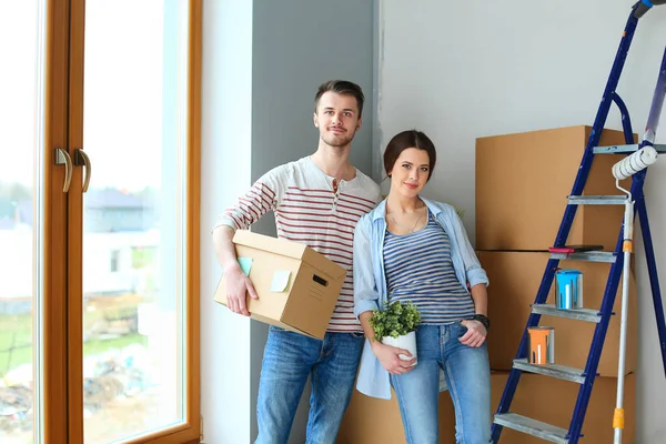 Feliz jovem casal desembalagem ou embalagem caixas e se mudar para uma nova casa — Fotografia de Stock