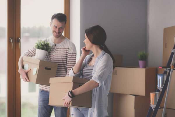 Счастливая молодая пара распаковывает коробки и переезжает в новый дом
