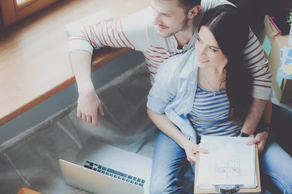 Jeune couple assis sur le sol de leur nouvel appartement — Photo