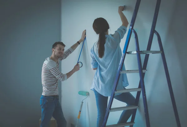 Portret van gelukkig lachend jong koppel schilderij interieur wand nieuw huis — Stockfoto