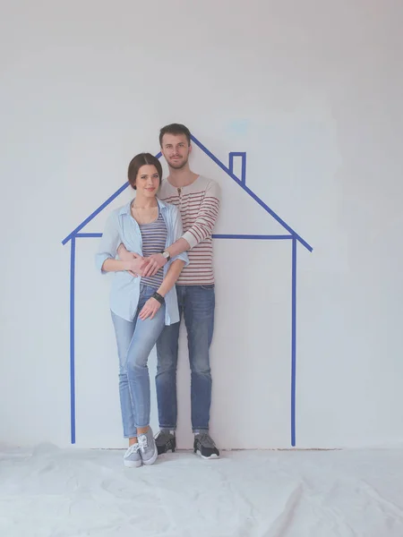 Couple standing in front of painted home on wall — Stock Photo, Image