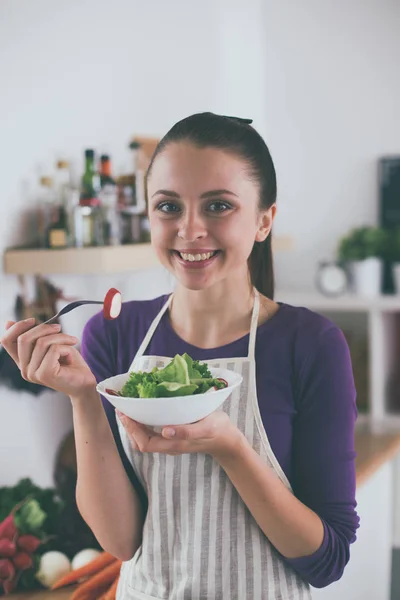 Jonge vrouw die verse salade eet in de moderne keuken — Stockfoto