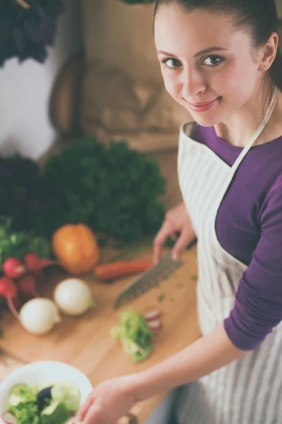 Mujer joven cortando verduras en la cocina — Foto de Stock