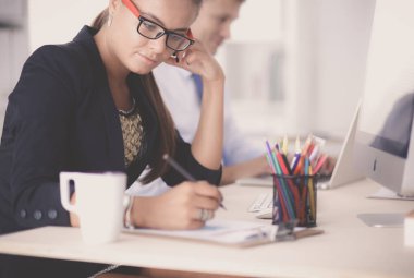 Moda tasarımcıları stüdyoda çalışıyor. Masanın üzerinde oturuyorlar.