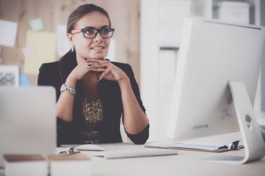 Moda tasarımcıları stüdyoda çalışıyor. Masanın üzerinde oturuyorlar.