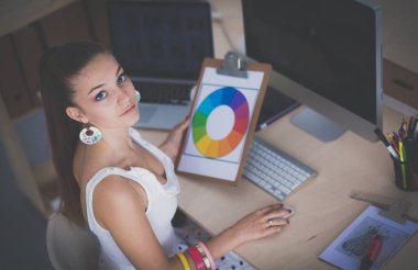 Ofiste çalışan genç bir kadın, masada oturuyor.