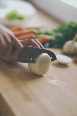 Mutfakta sebze doğrayan genç bir kadın.