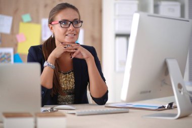 Moda tasarımcıları stüdyoda çalışıyor. Masanın üzerinde oturuyorlar.