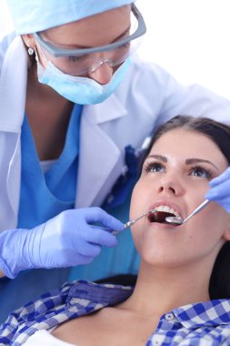 Kadın dişçi hastalarının dişlerinde çalışıyor.
