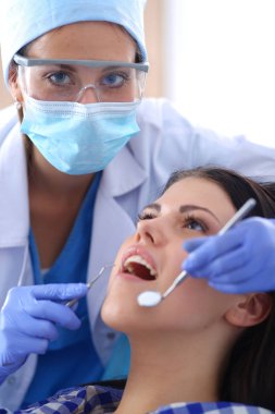 Kadın dişçi hastalarının dişlerinde çalışıyor.