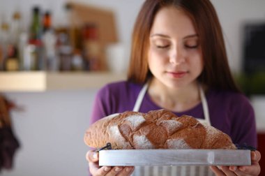 Genç bir kadın mutfağında lezzetli taze ekmek tutuyor.